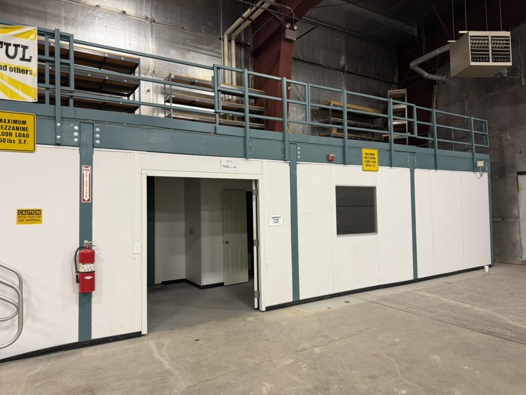 Enclosed tool room with racked mezzanine storage above